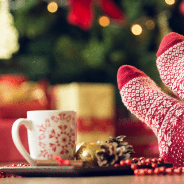 feet in christmas socks up on a table, christmas mug next to them featured image