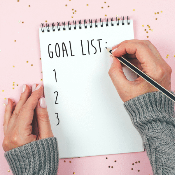 featured image of womans hands holding a pen and writing down three goals for 2024