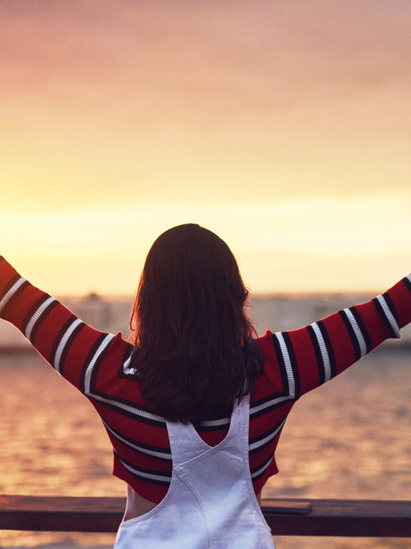 woman with wide opened hands watching the sunset