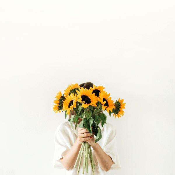 woman holding sunflowers in front of her face