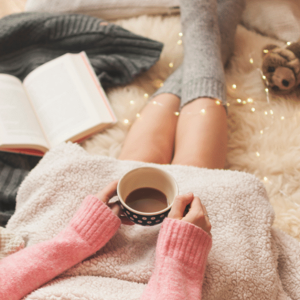 featured photo of a woman holding a cup of coffee while cosying up on the floor with a journal