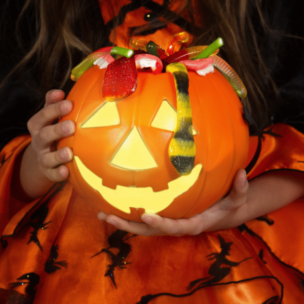 a woman holding Halloween pumpkin carved with scary face as a featured image for post for Halloween gift basket ideas for adults