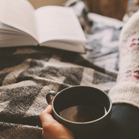 featured photo for post with December self-care challenge with a woman's feet in cozy socks holding a cup of coffee